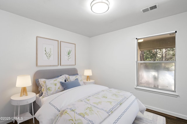 bedroom with wood finished floors, visible vents, and baseboards