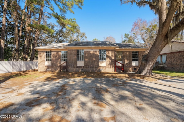 rear view of property featuring crawl space, entry steps, brick siding, and fence