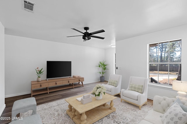 living area featuring visible vents, ceiling fan, baseboards, and wood finished floors