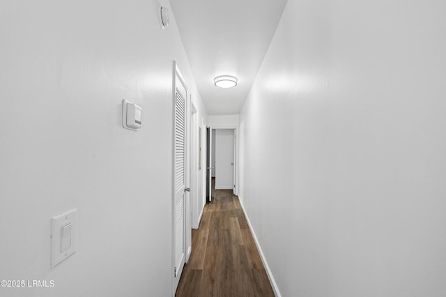 corridor with baseboards and dark wood-style flooring