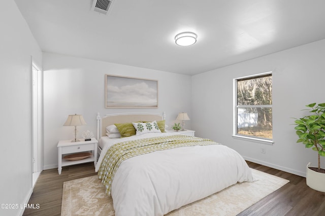 bedroom featuring visible vents, baseboards, and wood finished floors