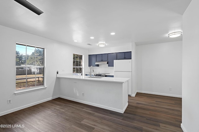 kitchen featuring a wealth of natural light, a peninsula, freestanding refrigerator, and light countertops