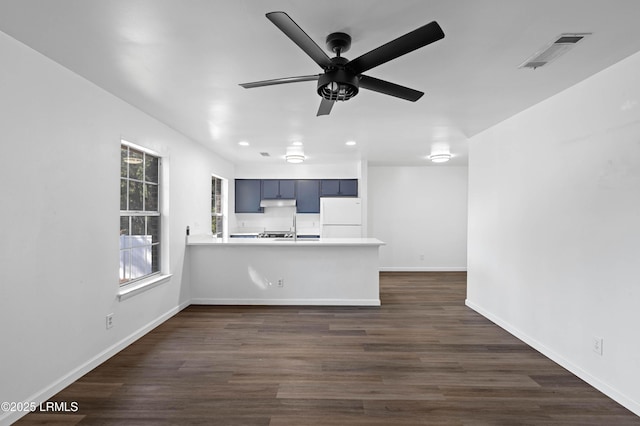 kitchen with dark wood-style floors, visible vents, a peninsula, and freestanding refrigerator