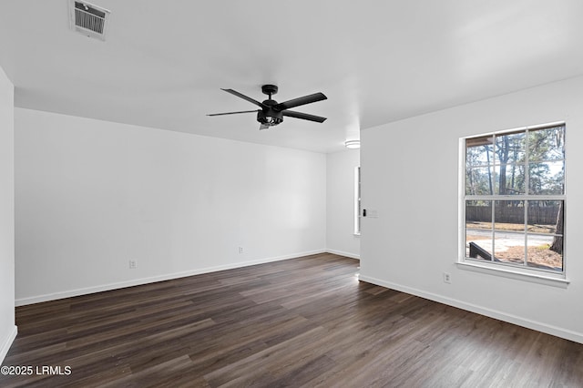 spare room with dark wood finished floors, baseboards, visible vents, and ceiling fan