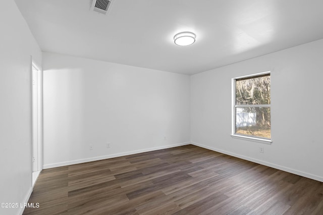 unfurnished room featuring visible vents, baseboards, and dark wood finished floors