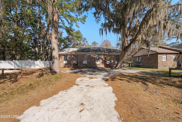 ranch-style house with crawl space, brick siding, driveway, and fence