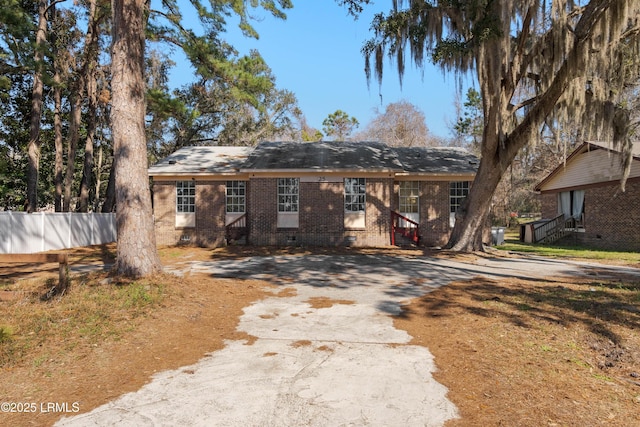 view of front of house featuring entry steps, fence, brick siding, and crawl space