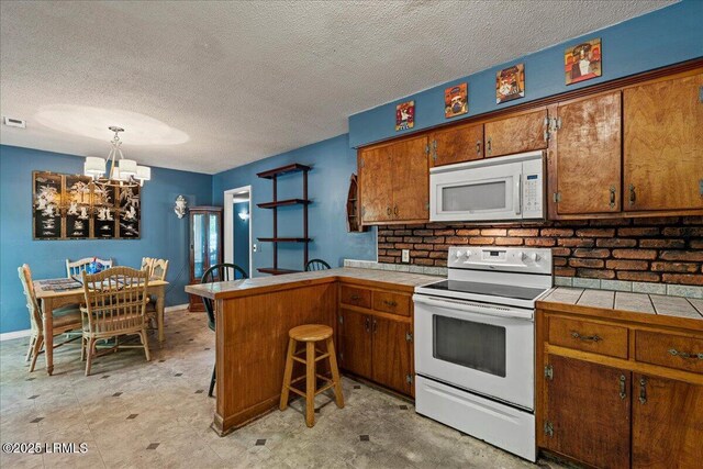 3003 Cherry Blvd, Beaufort, SC 29902 - kitchen with white appliances, tile countertops, a peninsula, brown cabinetry, and a chandelier