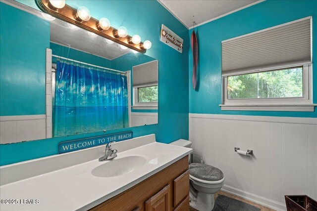 3003 Cherry Blvd, Beaufort, SC 29902 - bathroom featuring wainscoting, toilet, vanity, a decorative wall, and curtained shower