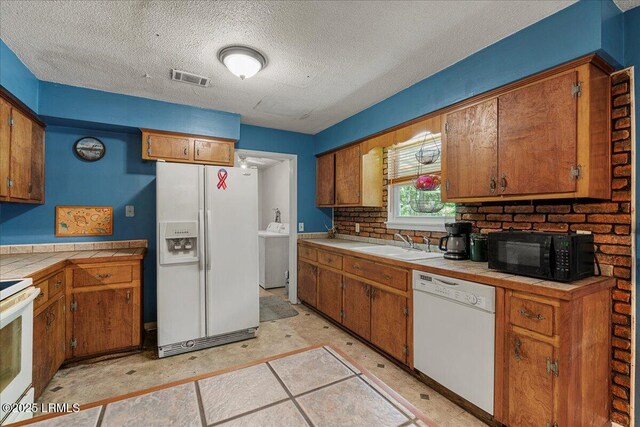 3003 Cherry Blvd, Beaufort, SC 29902 - kitchen featuring white appliances, tile countertops, a sink, washer / clothes dryer, and brown cabinets