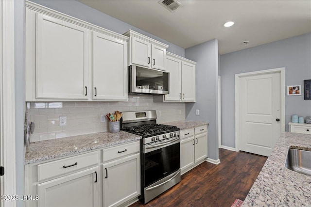 kitchen featuring backsplash, stainless steel appliances, light stone countertops, and white cabinets