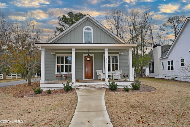 bungalow-style home with a yard and covered porch