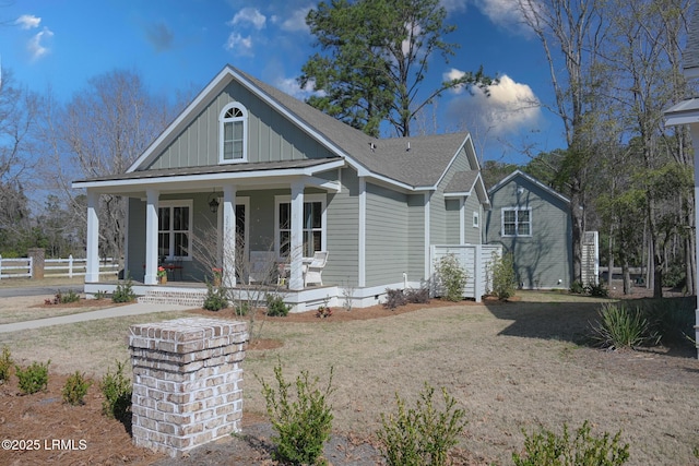 view of front of property featuring board and batten siding, a front yard, a porch, and fence