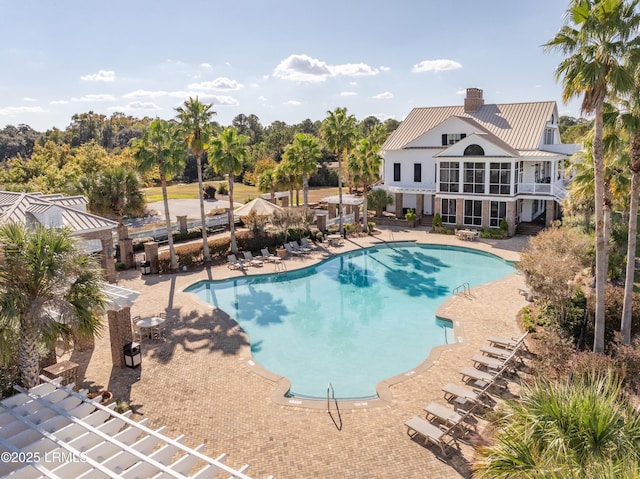 community pool with a patio area, fence, and stairway