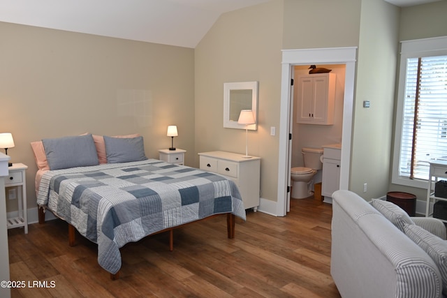 bedroom featuring lofted ceiling, ensuite bath, baseboards, and wood finished floors