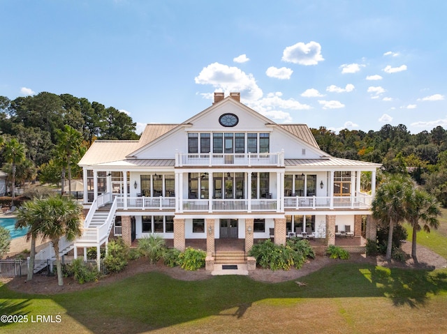 back of house featuring a balcony, a yard, stairway, a standing seam roof, and a patio area