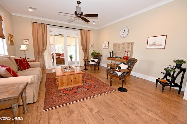 living area featuring baseboards, visible vents, a ceiling fan, ornamental molding, and wood finished floors