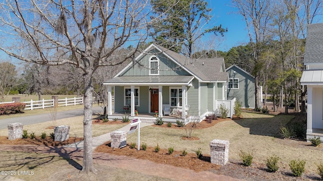 view of front of home featuring driveway, metal roof, fence, and a porch