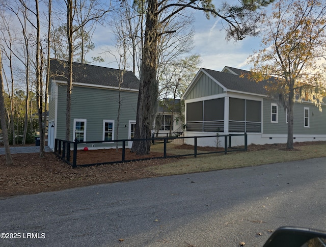 view of property exterior with a shingled roof, fence, a sunroom, crawl space, and board and batten siding