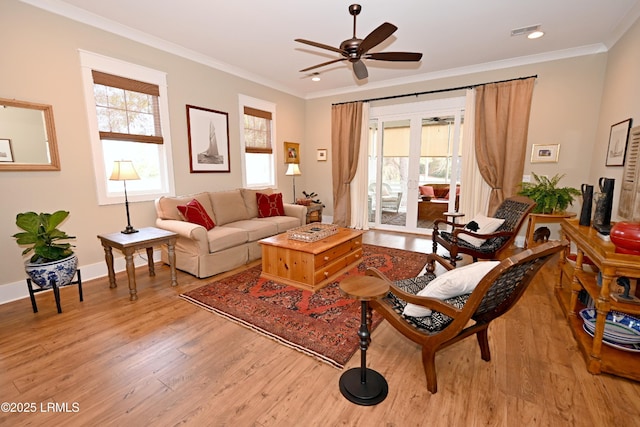 living area with ornamental molding, baseboards, visible vents, and light wood finished floors