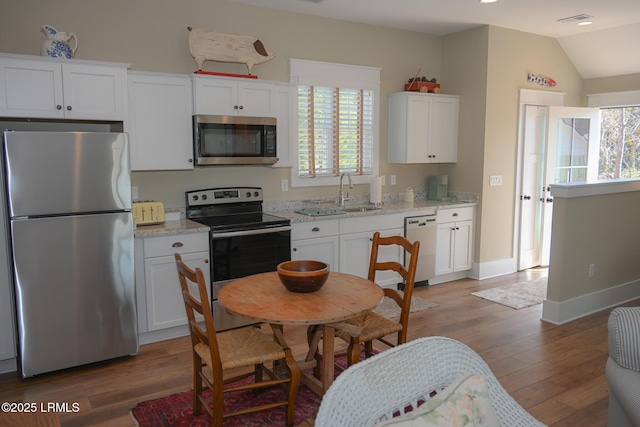 kitchen featuring stainless steel appliances, white cabinets, a sink, and wood finished floors