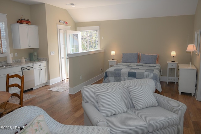 bedroom with lofted ceiling, light wood finished floors, visible vents, and baseboards