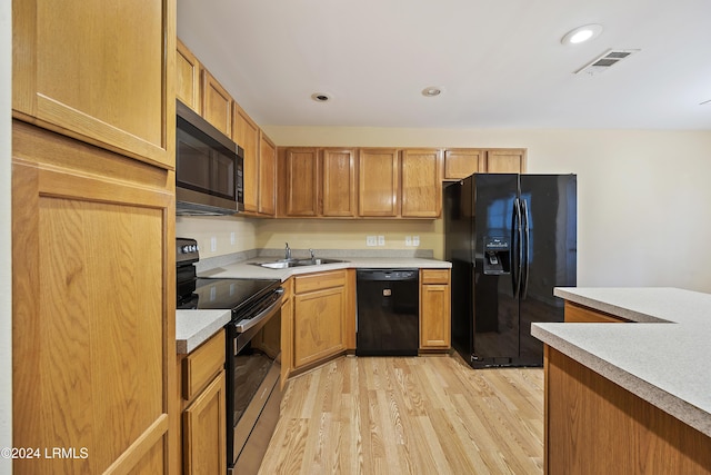 kitchen featuring sink, light hardwood / wood-style flooring, and black appliances