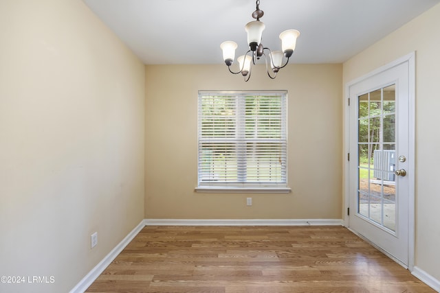 unfurnished dining area featuring wood-type flooring and a chandelier