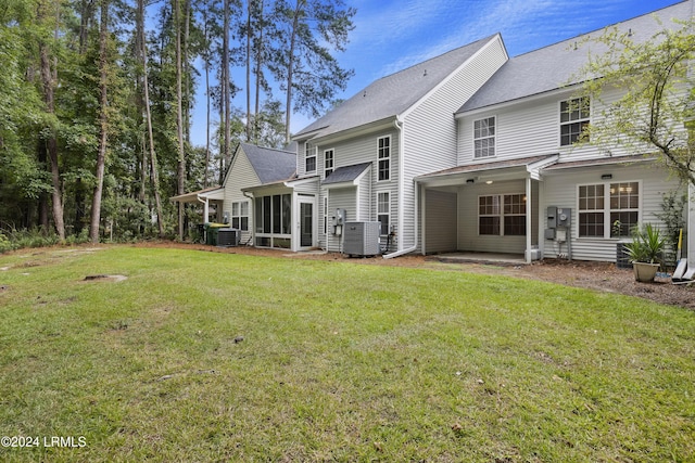 rear view of property featuring cooling unit, a sunroom, and a lawn