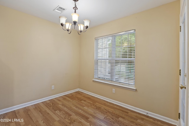 unfurnished room with an inviting chandelier and hardwood / wood-style floors