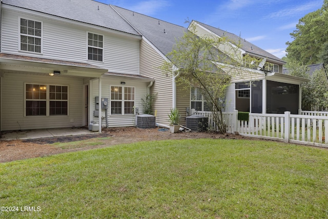 rear view of house with central AC, a patio, a sunroom, and a lawn