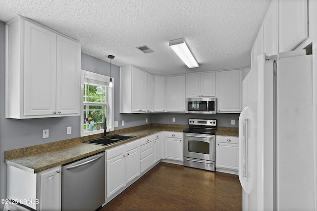 93 Heartstone Cir, Bluffton, SC 29910 - kitchen featuring appliances with stainless steel finishes, white cabinets, a textured ceiling, dark wood-style floors, and dark countertops