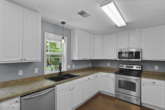 93 Heartstone Cir, Bluffton, SC 29910 - kitchen with stainless steel appliances, a sink, white cabinetry, dark countertops, and a textured ceiling