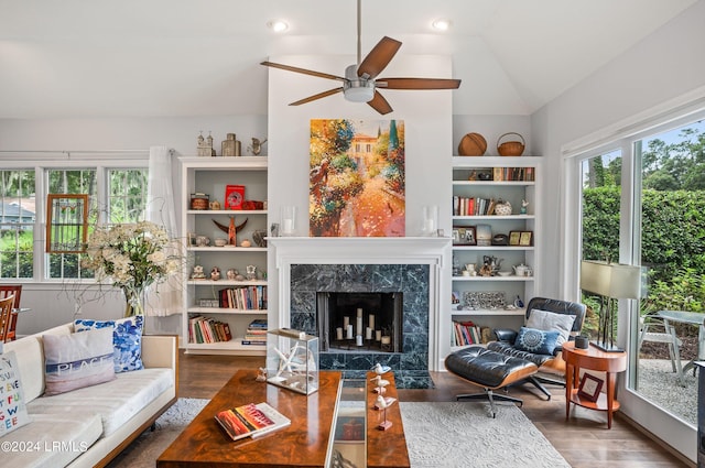 living room with dark hardwood / wood-style floors, ceiling fan, a premium fireplace, and vaulted ceiling