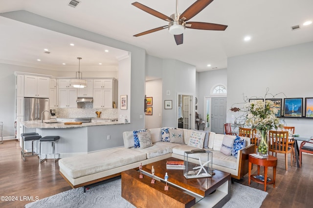 living room featuring ceiling fan, sink, and dark hardwood / wood-style flooring