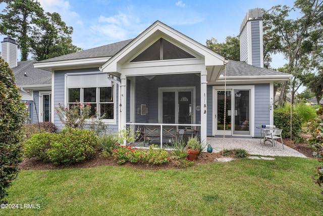 back of property with a yard, a patio area, and a sunroom