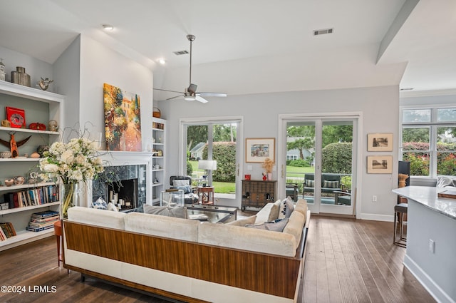 living room featuring dark hardwood / wood-style flooring, ceiling fan, a fireplace, and a healthy amount of sunlight