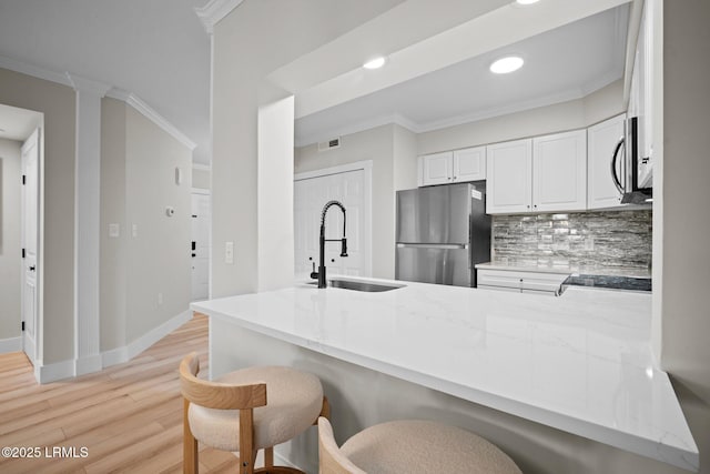 21 S Forest Beach Dr Unit 235, Hilton Head Island, SC 29928 - kitchen featuring a sink, appliances with stainless steel finishes, light wood-style floors, decorative backsplash, and ornamental molding