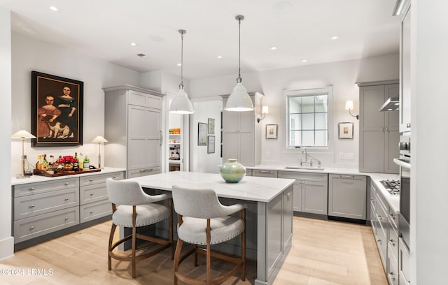 kitchen with a kitchen breakfast bar, sink, a kitchen island, and gray cabinetry