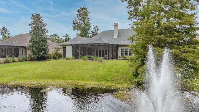 back of house featuring a yard, a water view, and glass enclosure