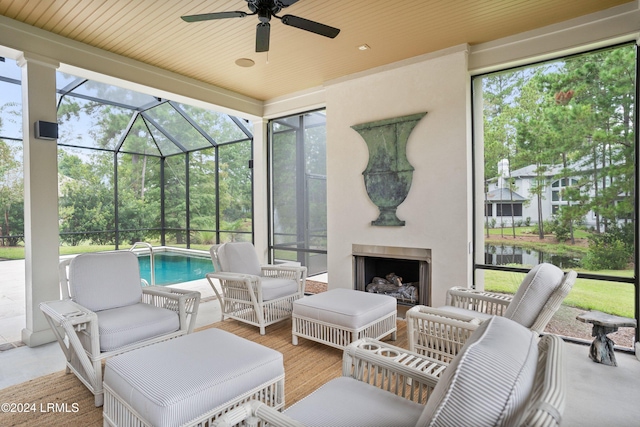 view of patio / terrace featuring an outdoor fireplace, ceiling fan, and glass enclosure