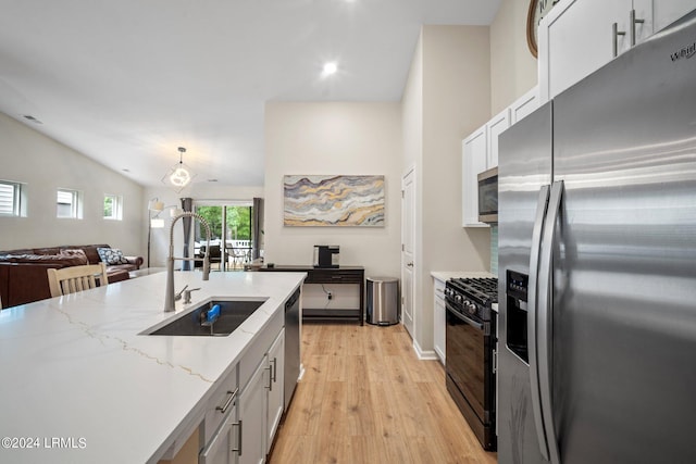 kitchen featuring lofted ceiling, sink, appliances with stainless steel finishes, white cabinets, and light wood-type flooring