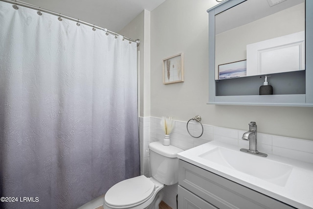 bathroom featuring vanity, toilet, and tile walls