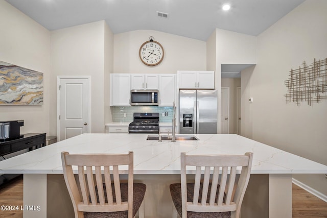 kitchen with white cabinetry, appliances with stainless steel finishes, a kitchen breakfast bar, and a kitchen island with sink