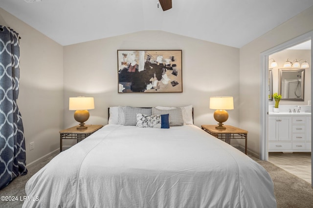 carpeted bedroom with ensuite bathroom, vaulted ceiling, and ceiling fan