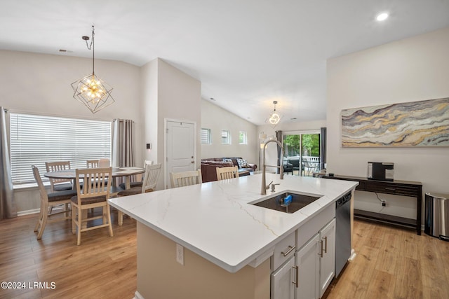 kitchen featuring sink, vaulted ceiling, stainless steel dishwasher, pendant lighting, and a kitchen island with sink