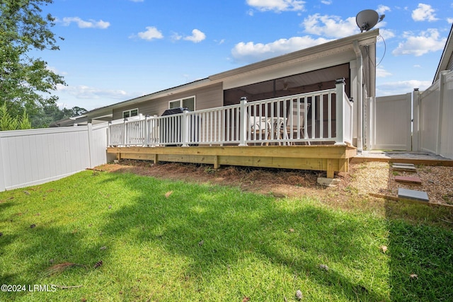 back of property with a wooden deck and a yard