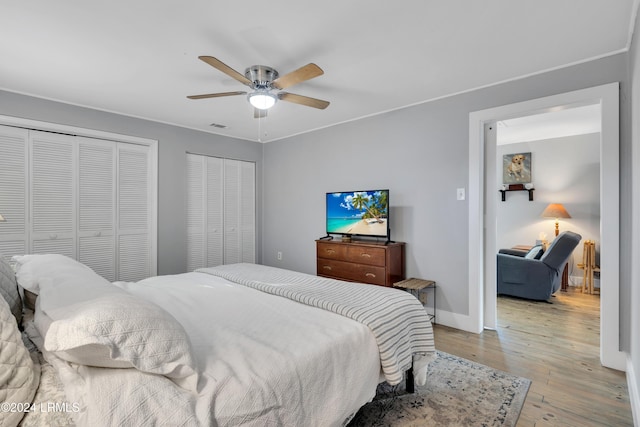 bedroom with multiple closets, ceiling fan, and light wood-type flooring