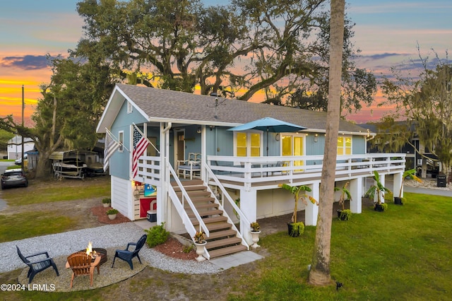 back house at dusk featuring a lawn, a deck, and an outdoor fire pit