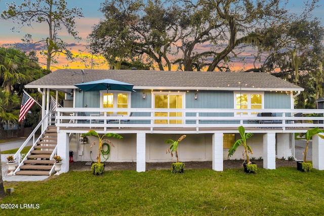 back house at dusk with a deck and a lawn